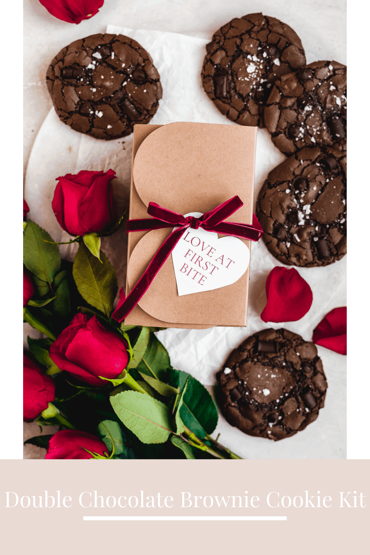 Brown box with red bow on a white surface with chocolate cookies and red roses.