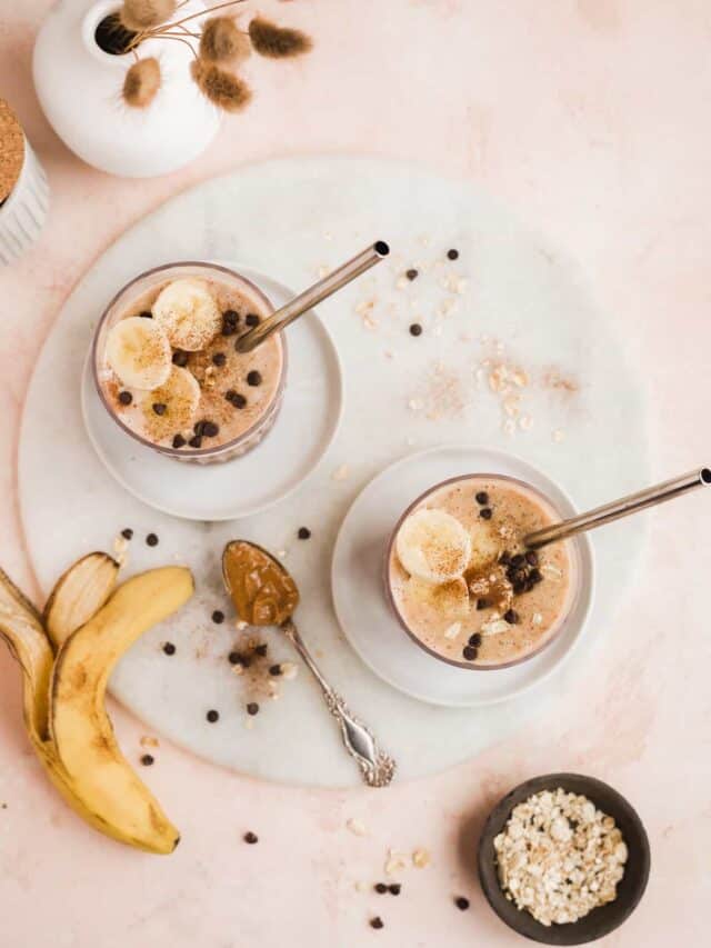 Overhead view of two banana bread smoothies in glasses with straws.