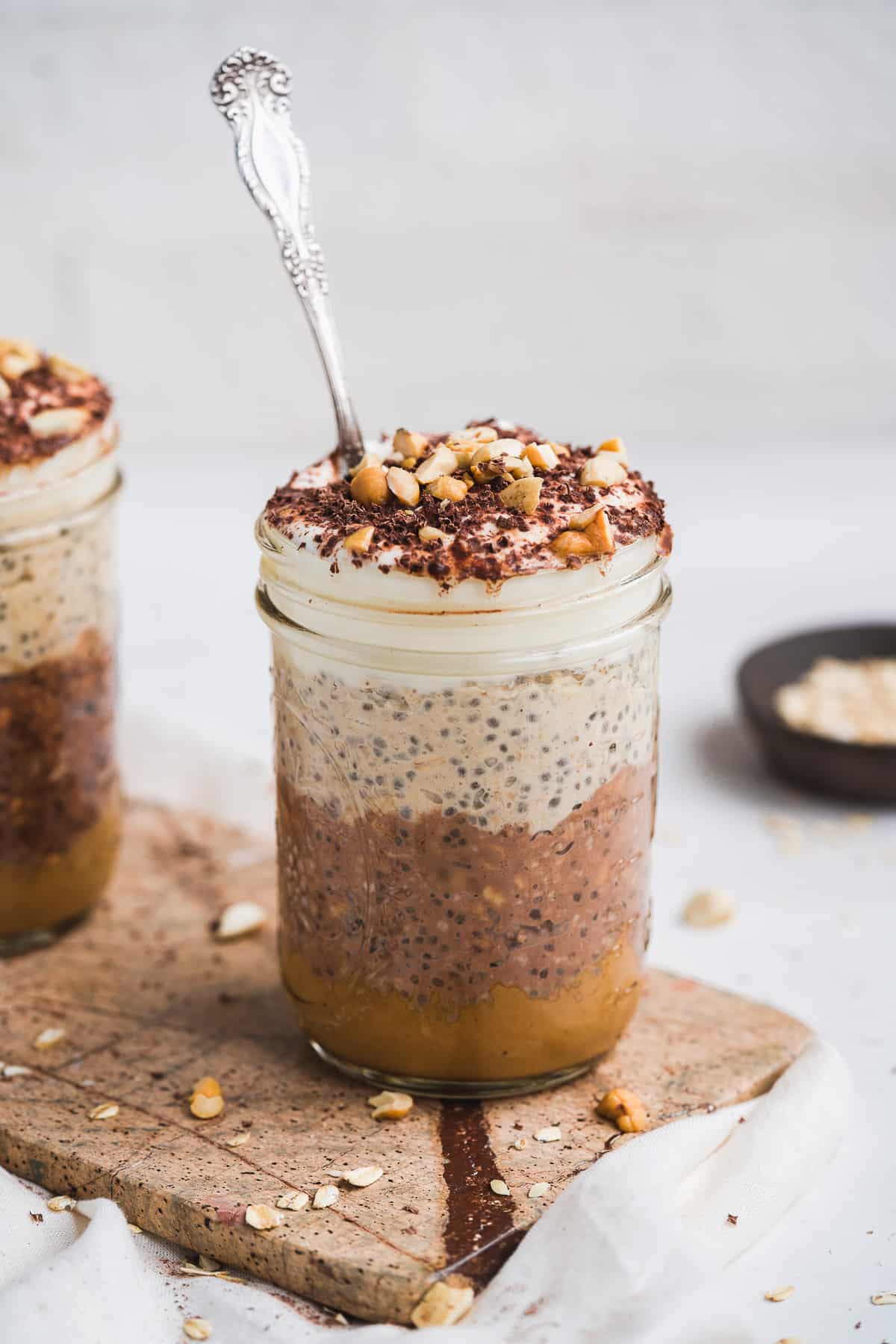 Jar of oats with chocolate oats and peanut butter oats on a tan marble board.