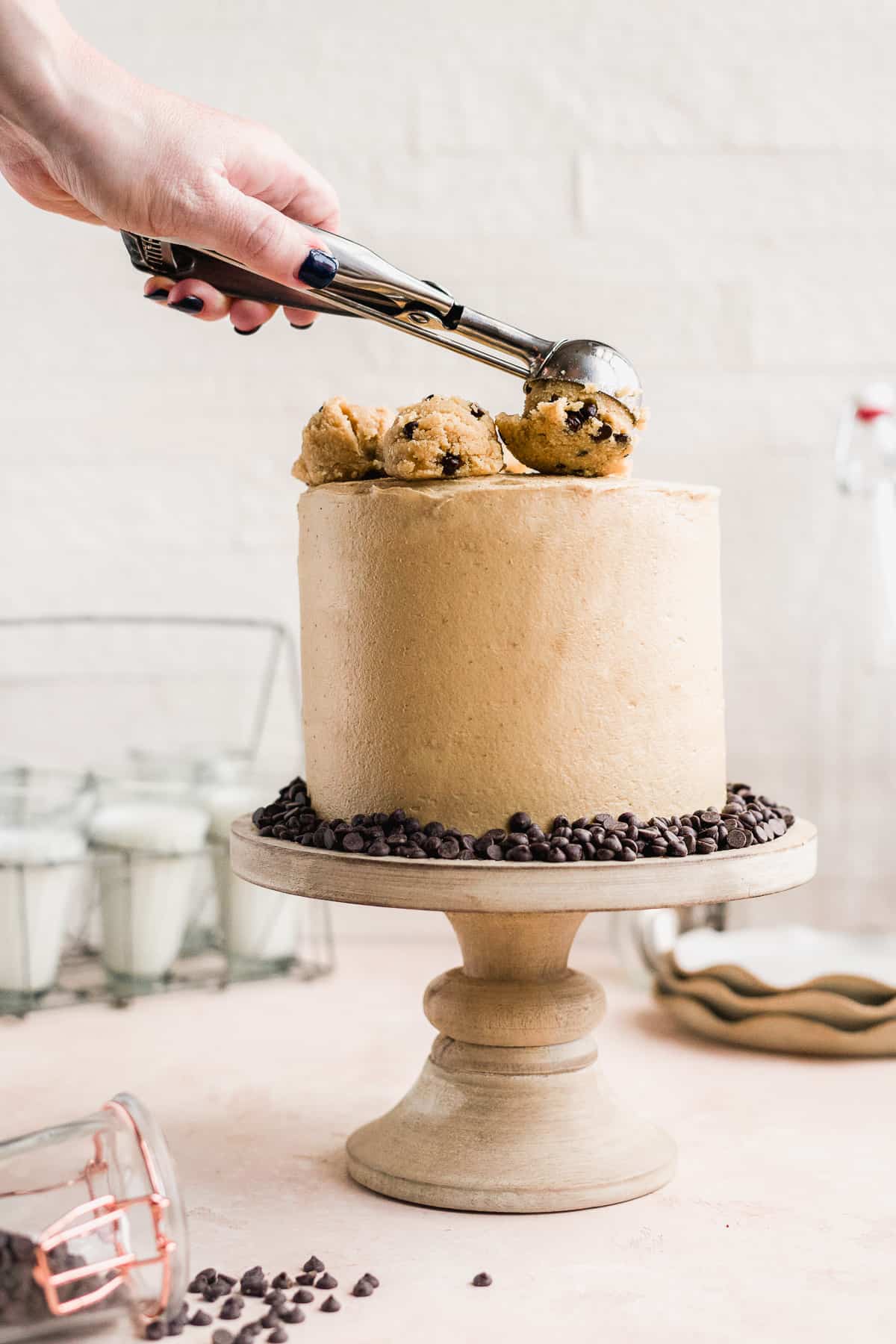Cake with a hand dropping scoop of cookie dough on top.