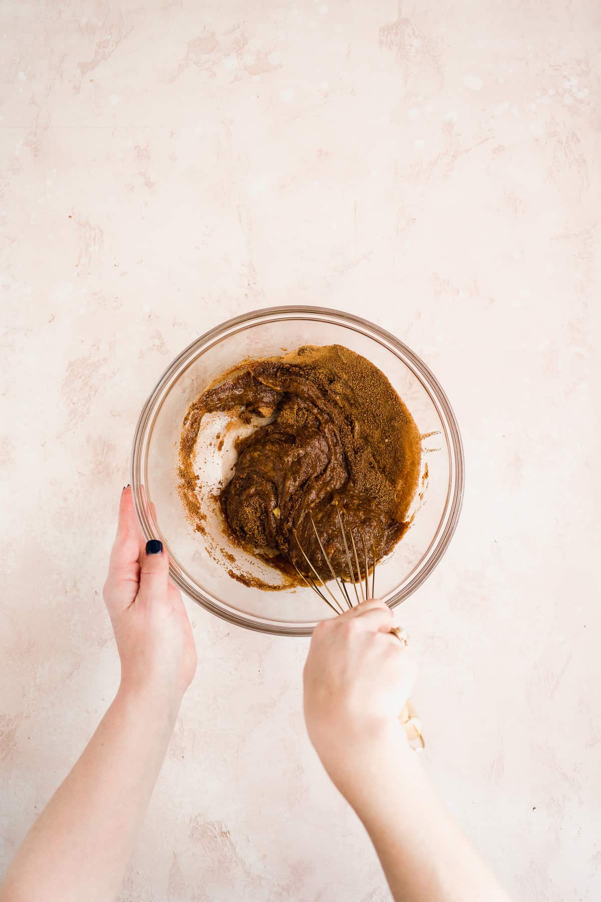 Person mixing cookie dough cake in a bowl with a whisk.