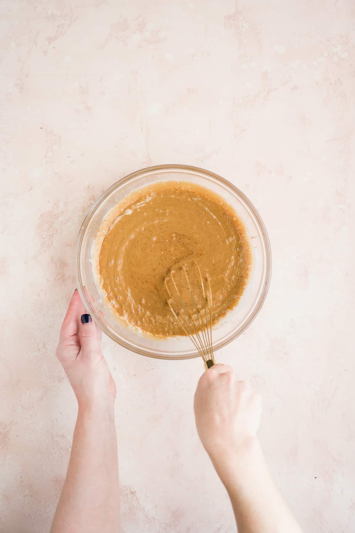 Person whisking cake batter in a large bowl.