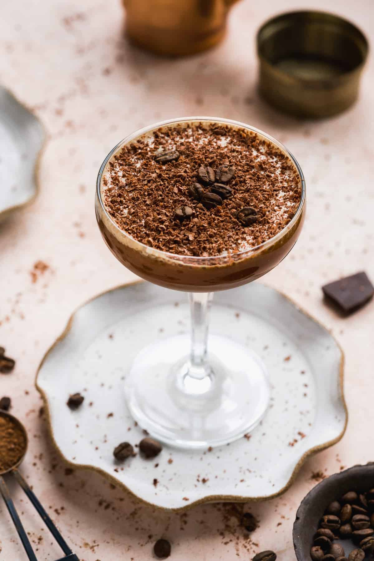 Cocktail glass on a plate with a chocolate drink and espresso beans.