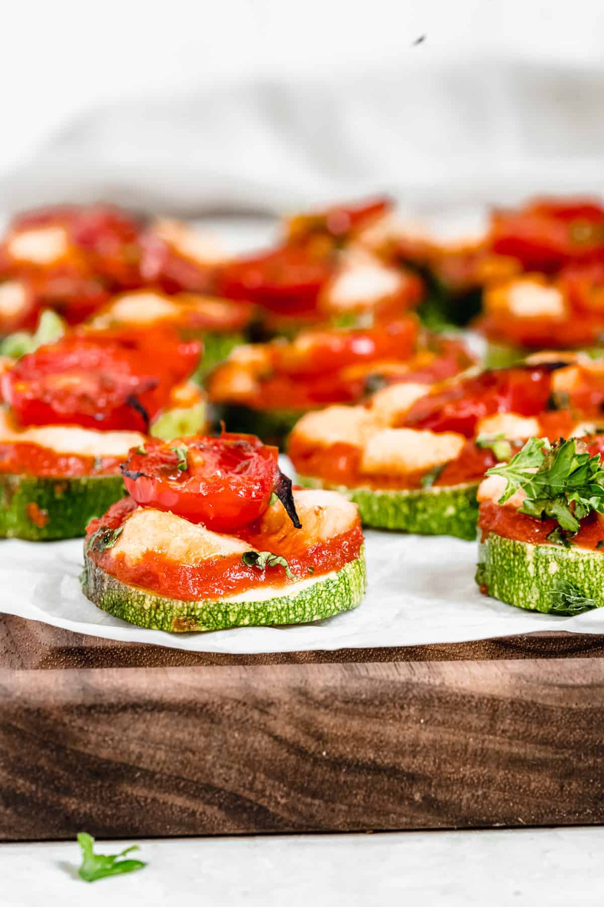 Wooden platter with white paper topped with zucchini pizza bites.