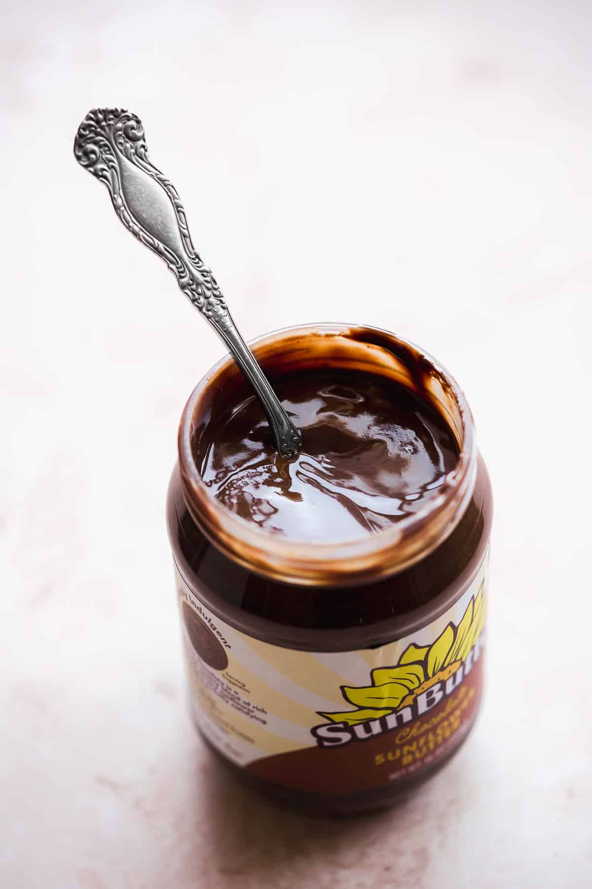 Jar of chocolate sunflower butter with a spoon resting in the jar.