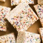Rice kripsie treats with sprinkles scattered on parchment paper.