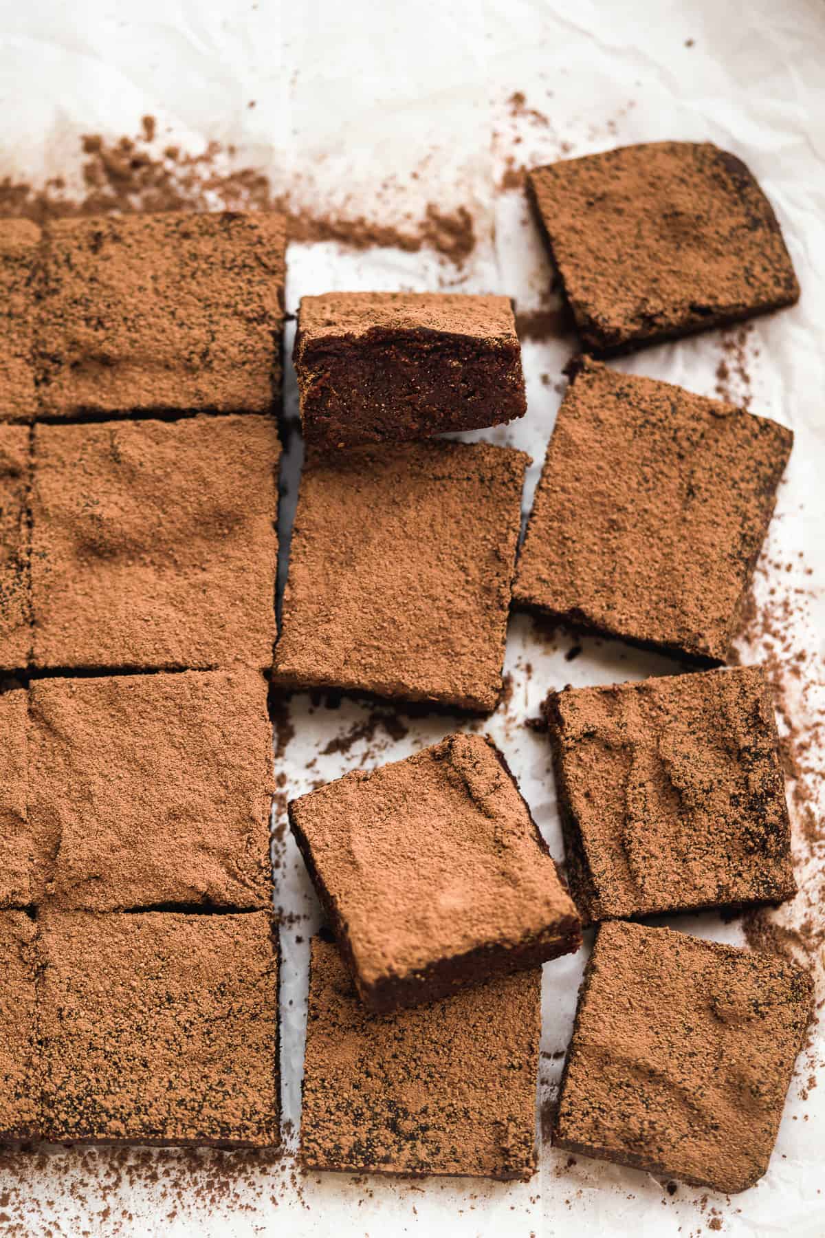 Line of brownies sliced into squares on a white piece of paper.