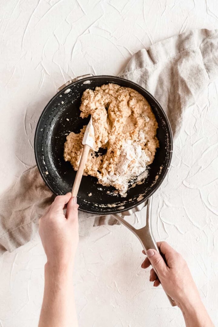 Person mixing dough in a skillet for baked churros.