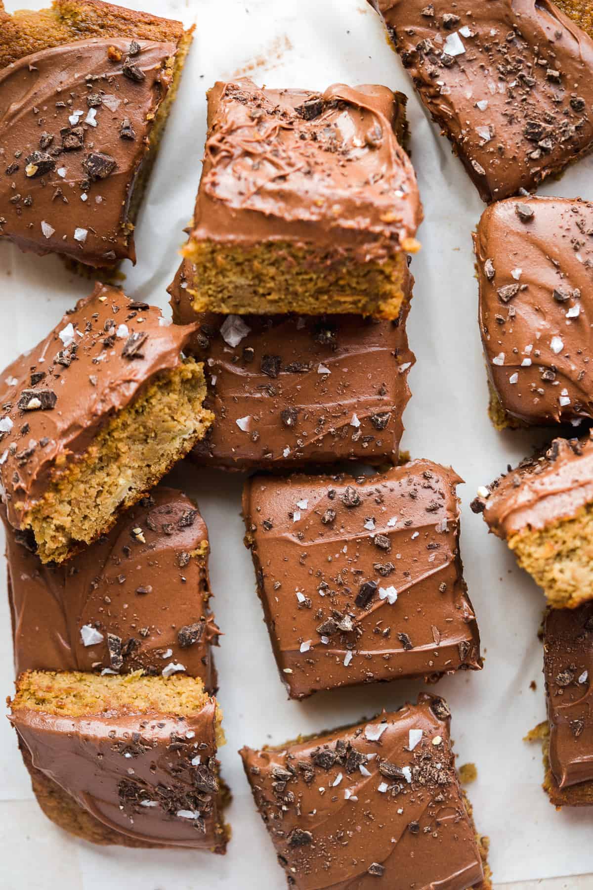 Pieces of cake with chocolate icing scattered on surface.