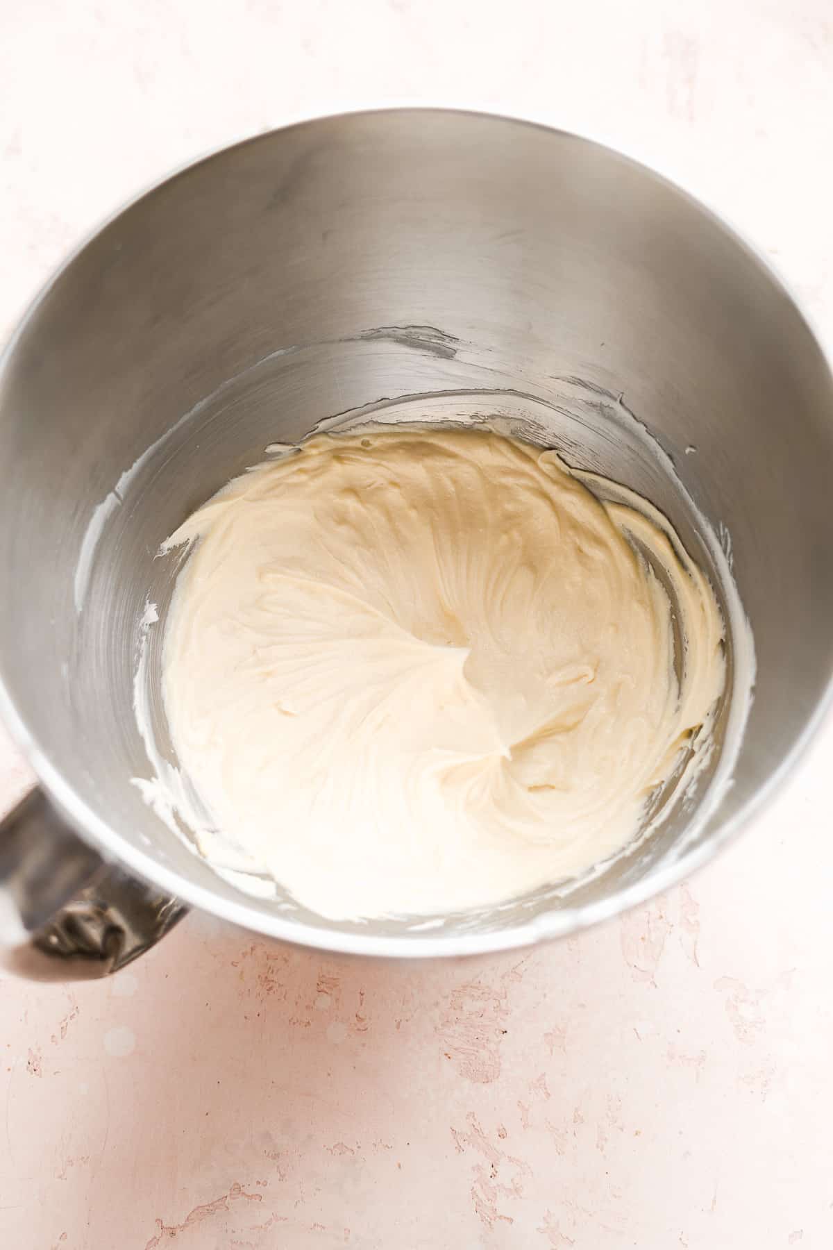 Cream cheese whipped inside a metal mixing bowl.