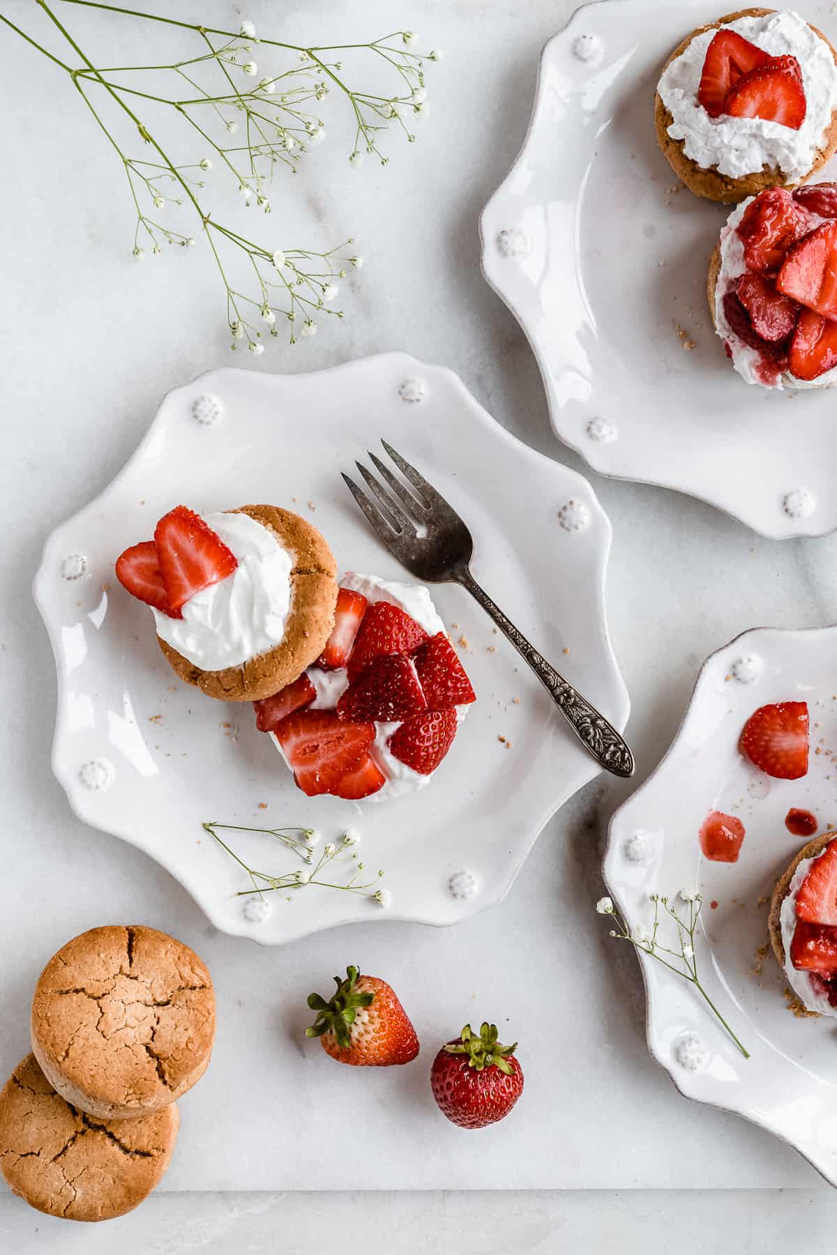 Overhead photo of a single Paleo Strawberry Shortcake Biscuit with the top slightly moved to show the delicious layers inside.  A silver fork lays nearby.  