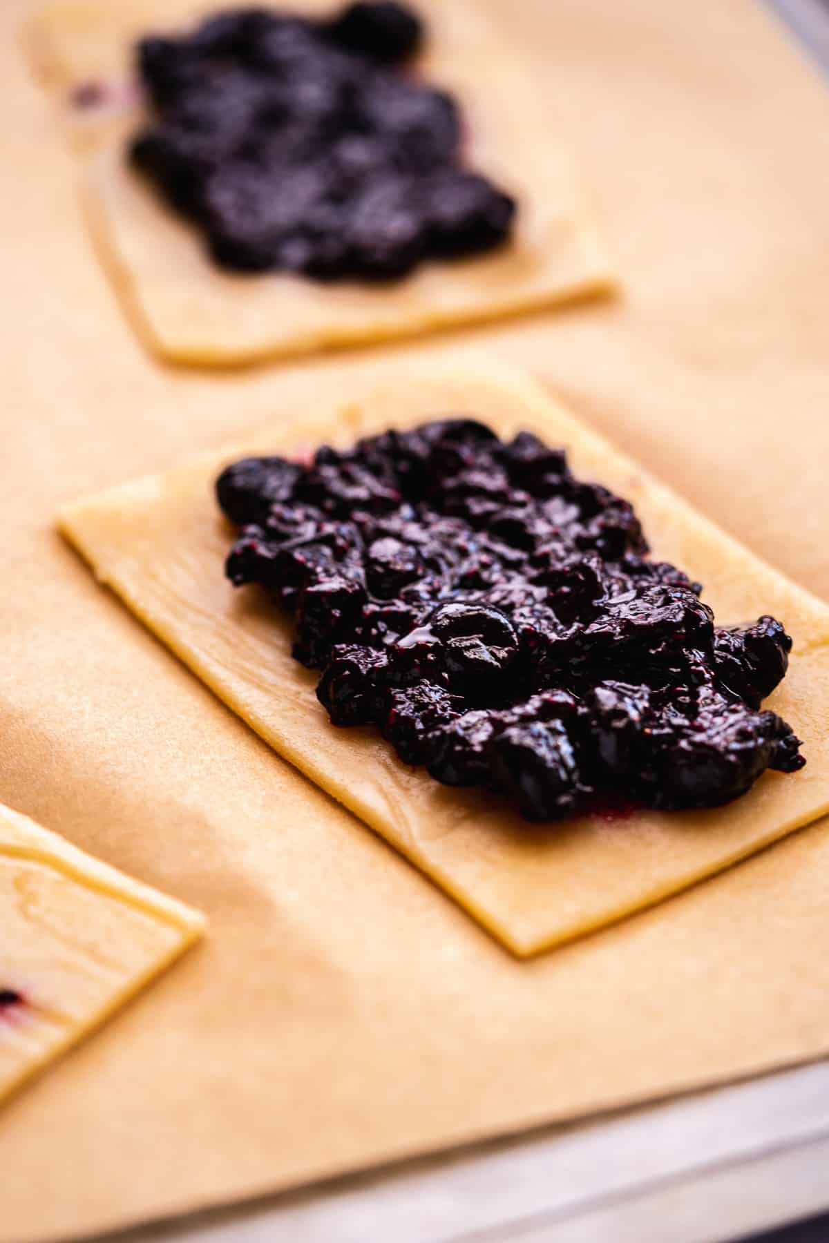Blueberry jam spread on top of a rectangular piece of pop tart dough.