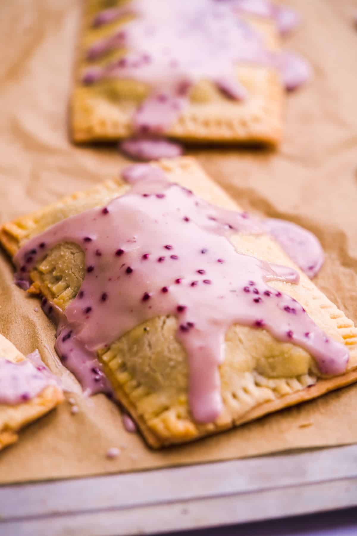 Blueberry pop tart with blueberry icing on top on parchment paper.