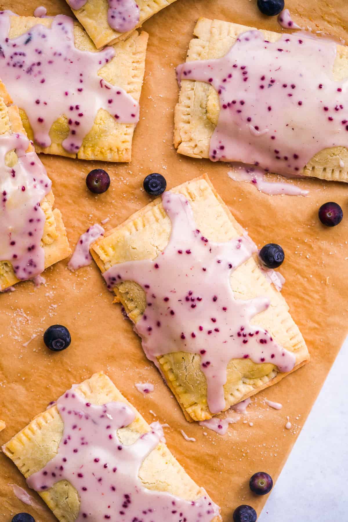 Gluten free blueberry pop tarts scattered on parchment paper.