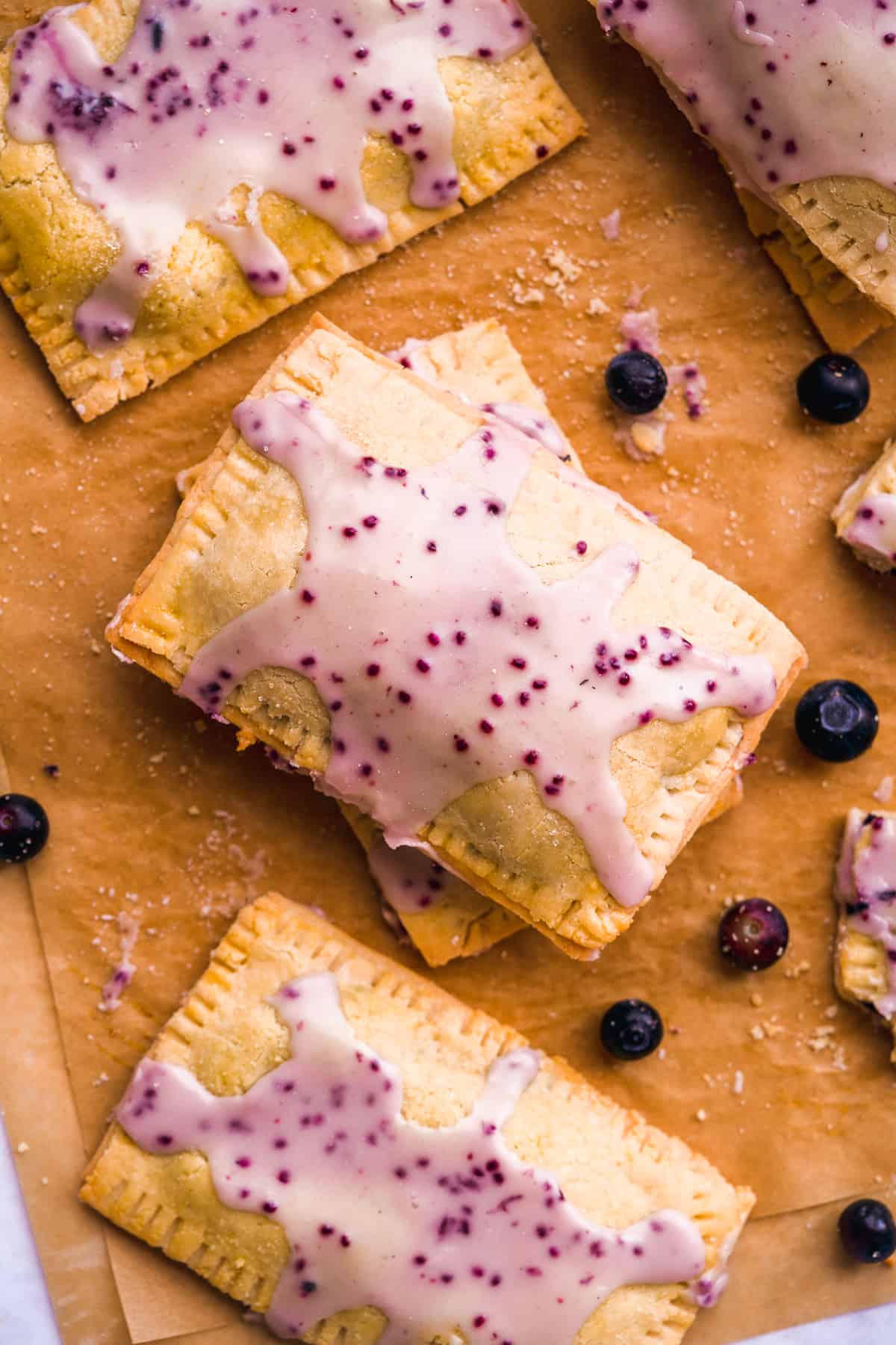 Gluten free pop tarts with blueberry icing on parchment paper.