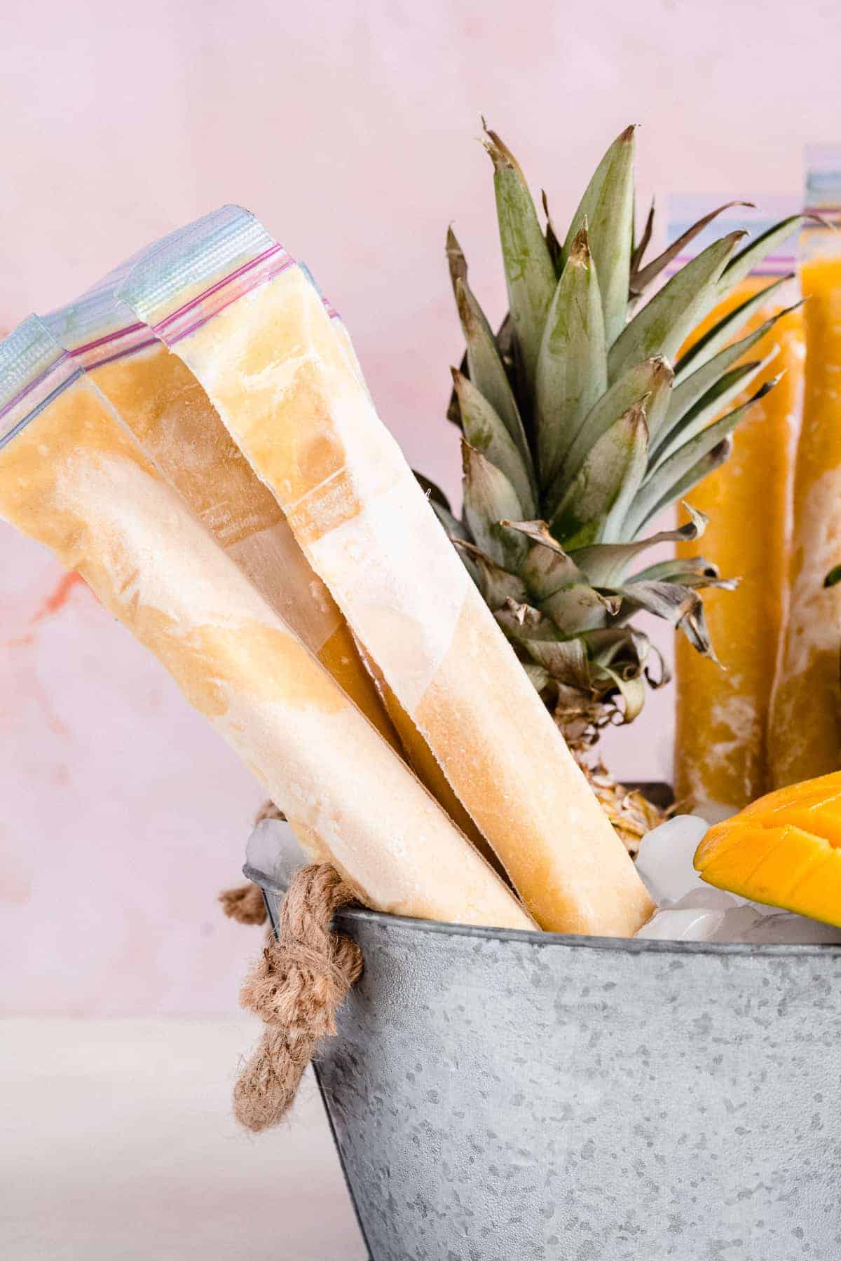 Yellow and orange frozen ice pops in ice bucket.