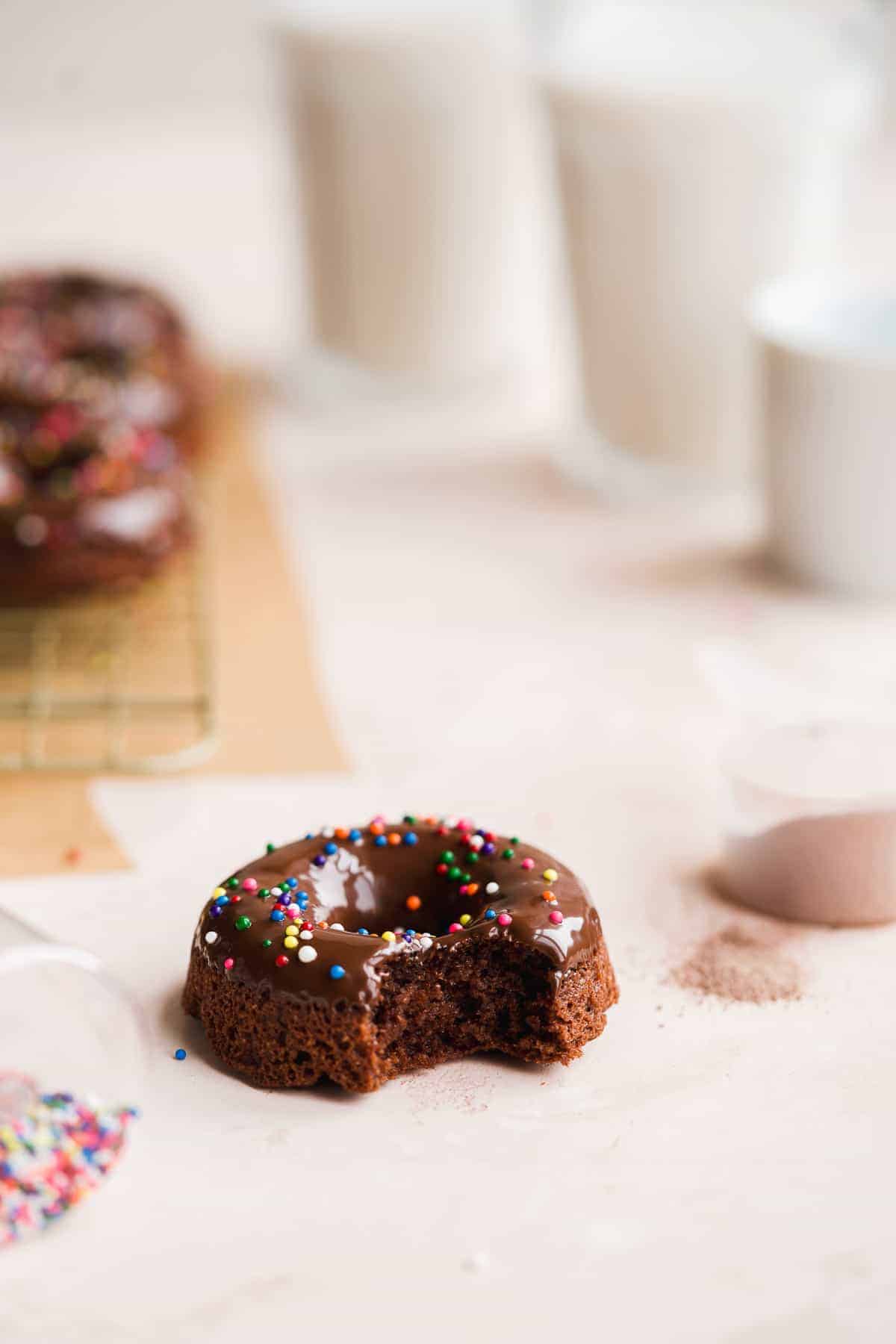 Bite taken out of chocolate doughnut with sprinkles.