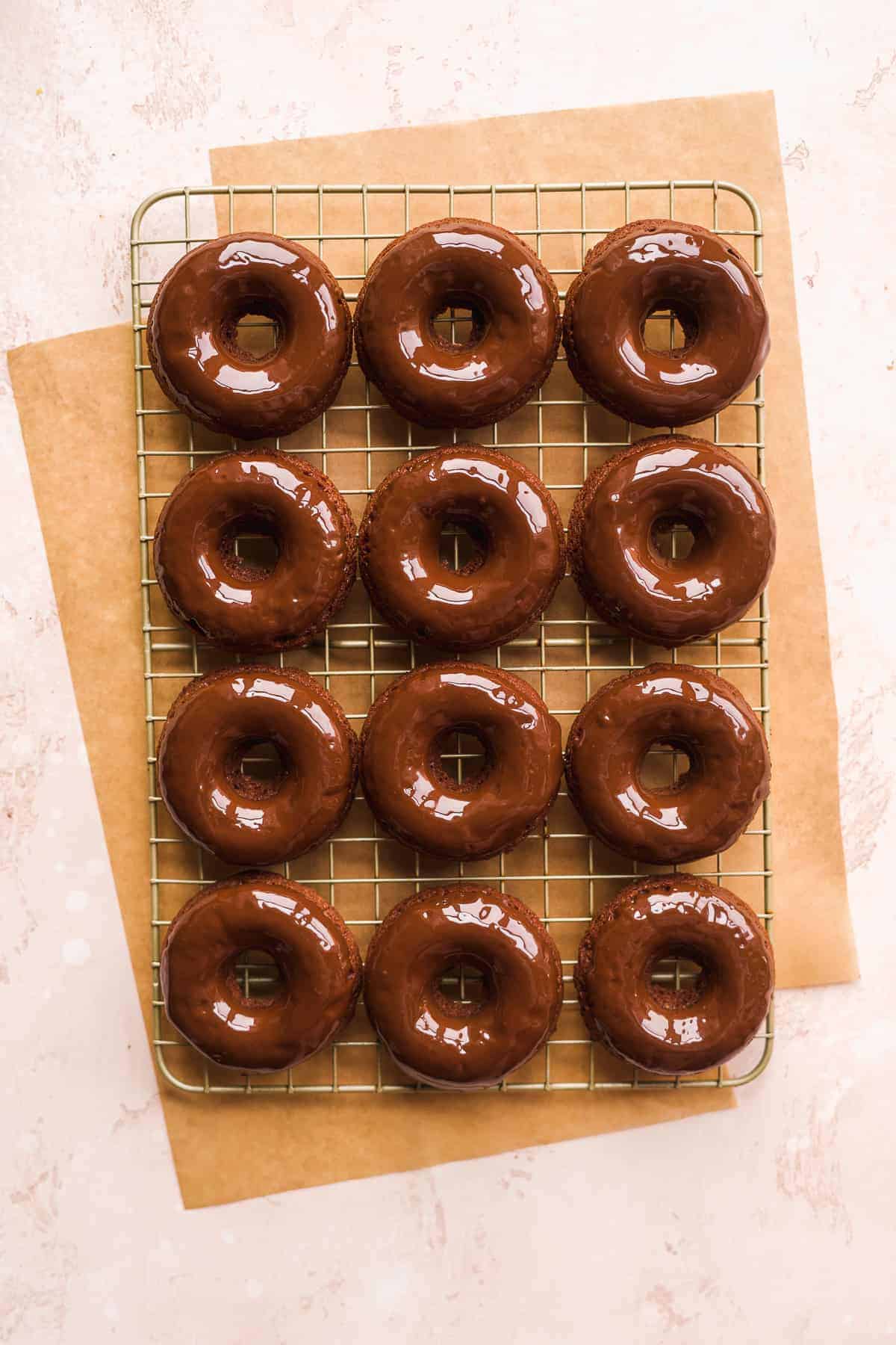 Chocolate doughnuts dipped in chocolate on wired rack.