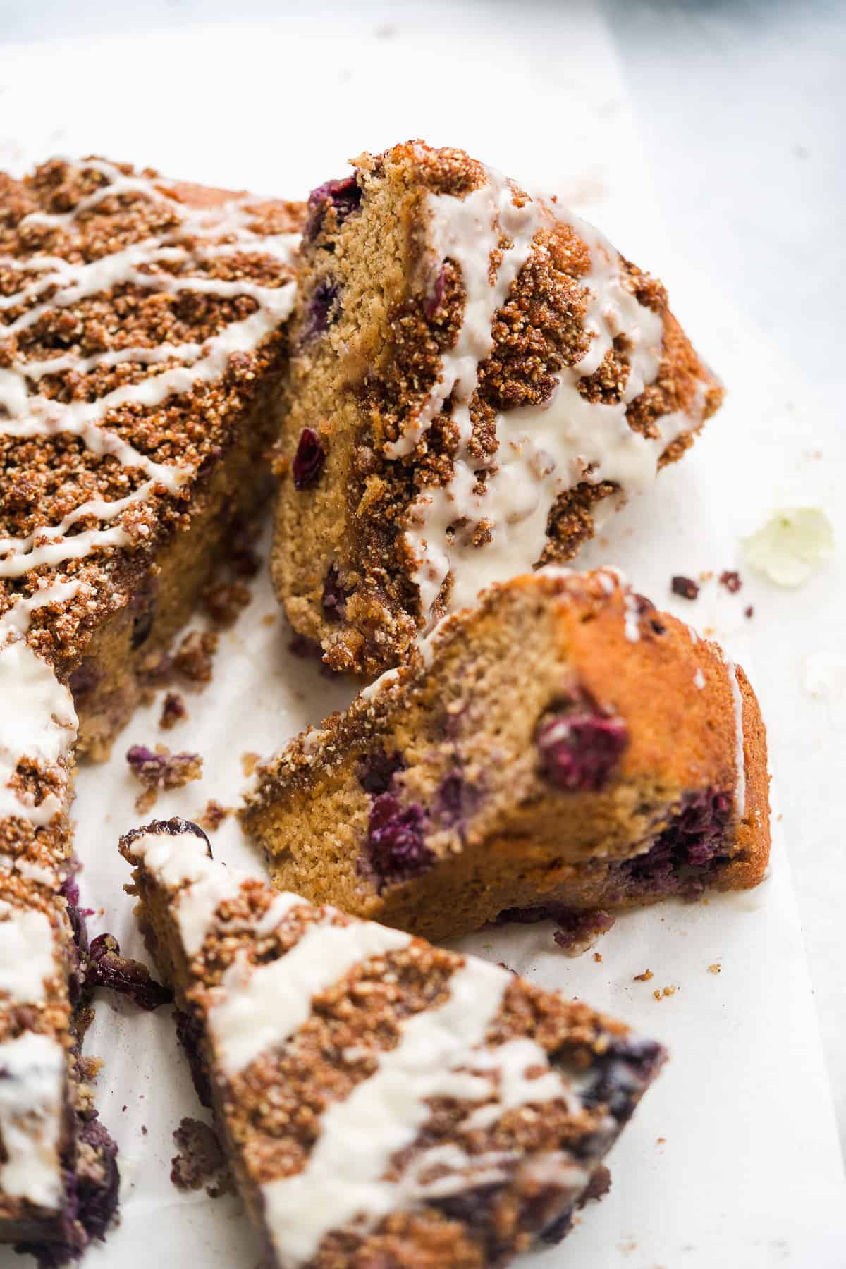 Coffee cake cut into triangles with blueberries and glaze scattered on surface.