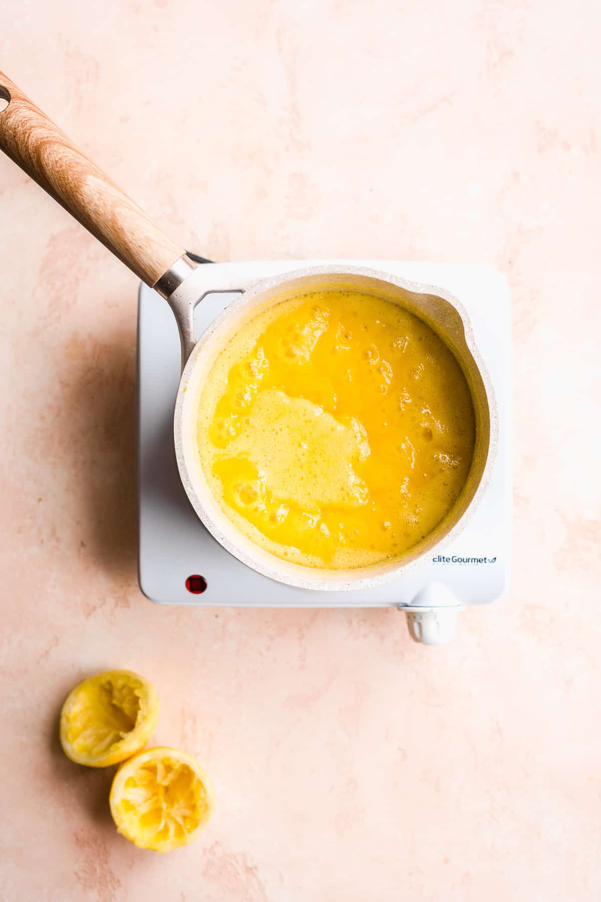 Lemon curd bubbling in a pot on a burner.