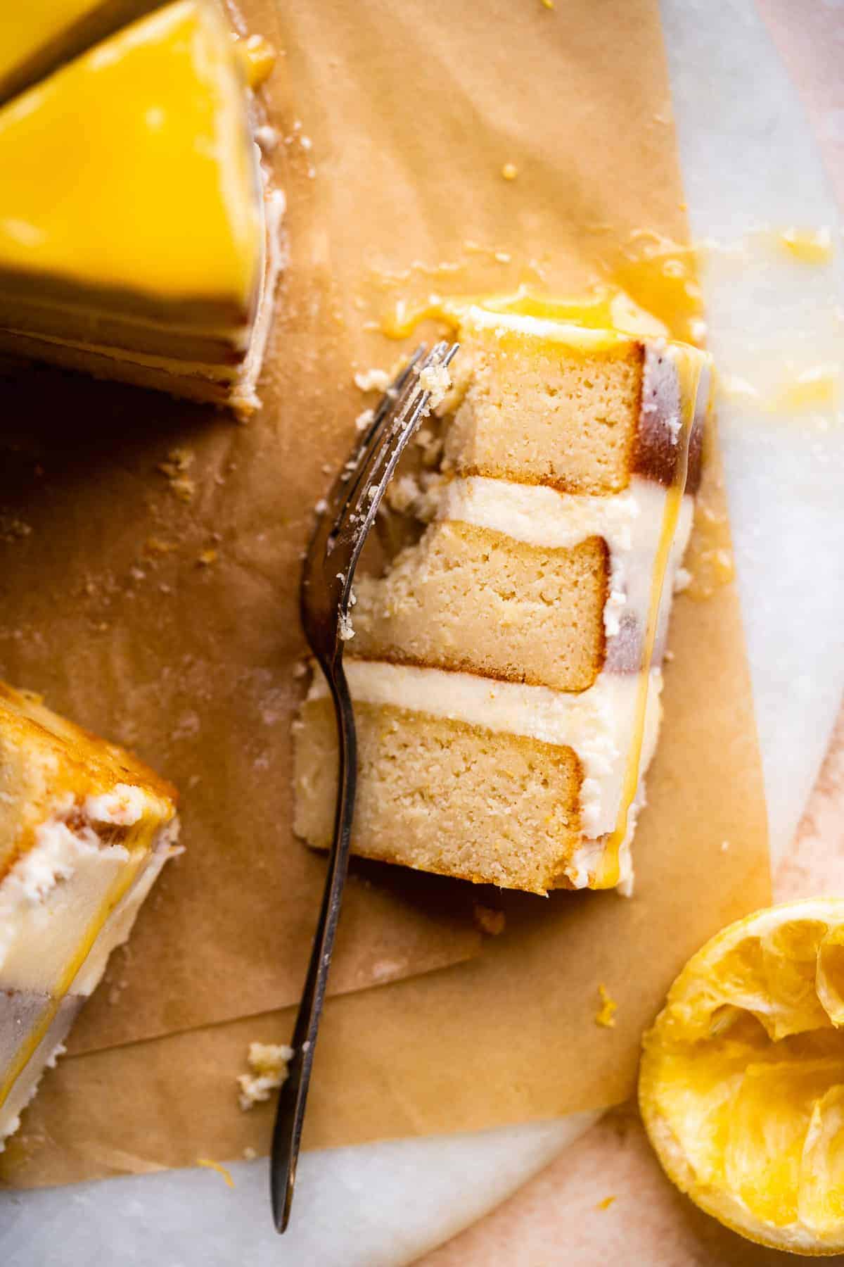 Piece of layer cake on brown paper with fork resting to the side.