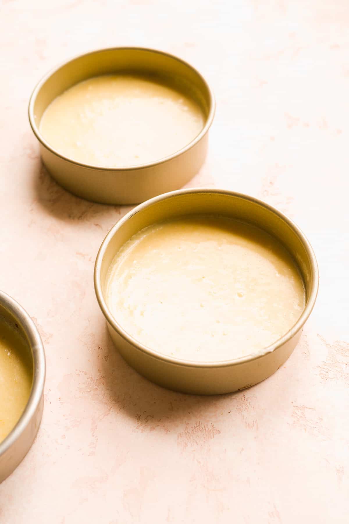 Cake pans filled halfway with cake batter.