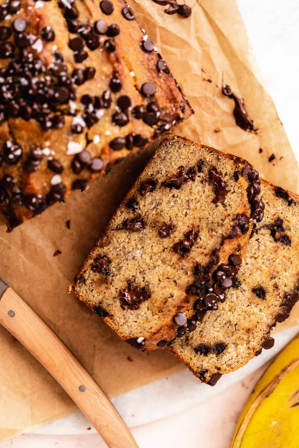 Slices of chocolate chip bread laying on top of one another on brown paper.