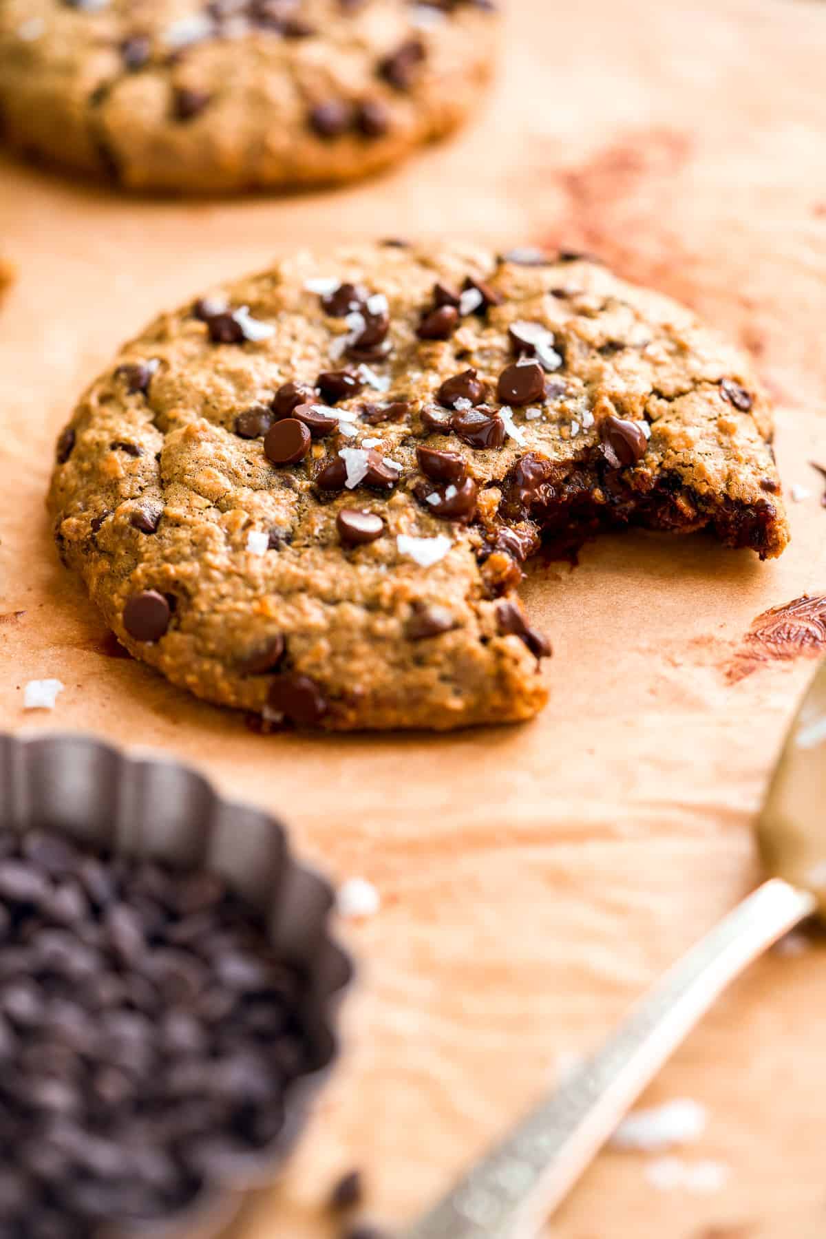 Oatmeal cookie with a bite taken out of it on brown parchment paper.