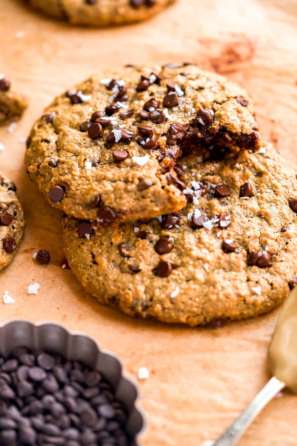 A chocolate chip cookie with a bite taken out of it on top of another cookie.