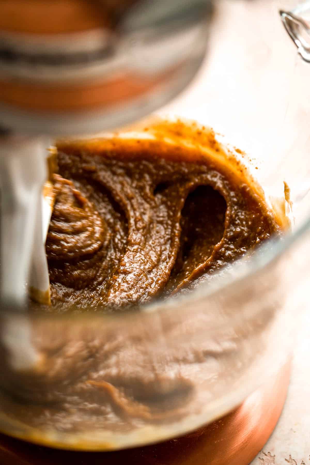 Tan batter in the bowl of a stand mixer with a beater.