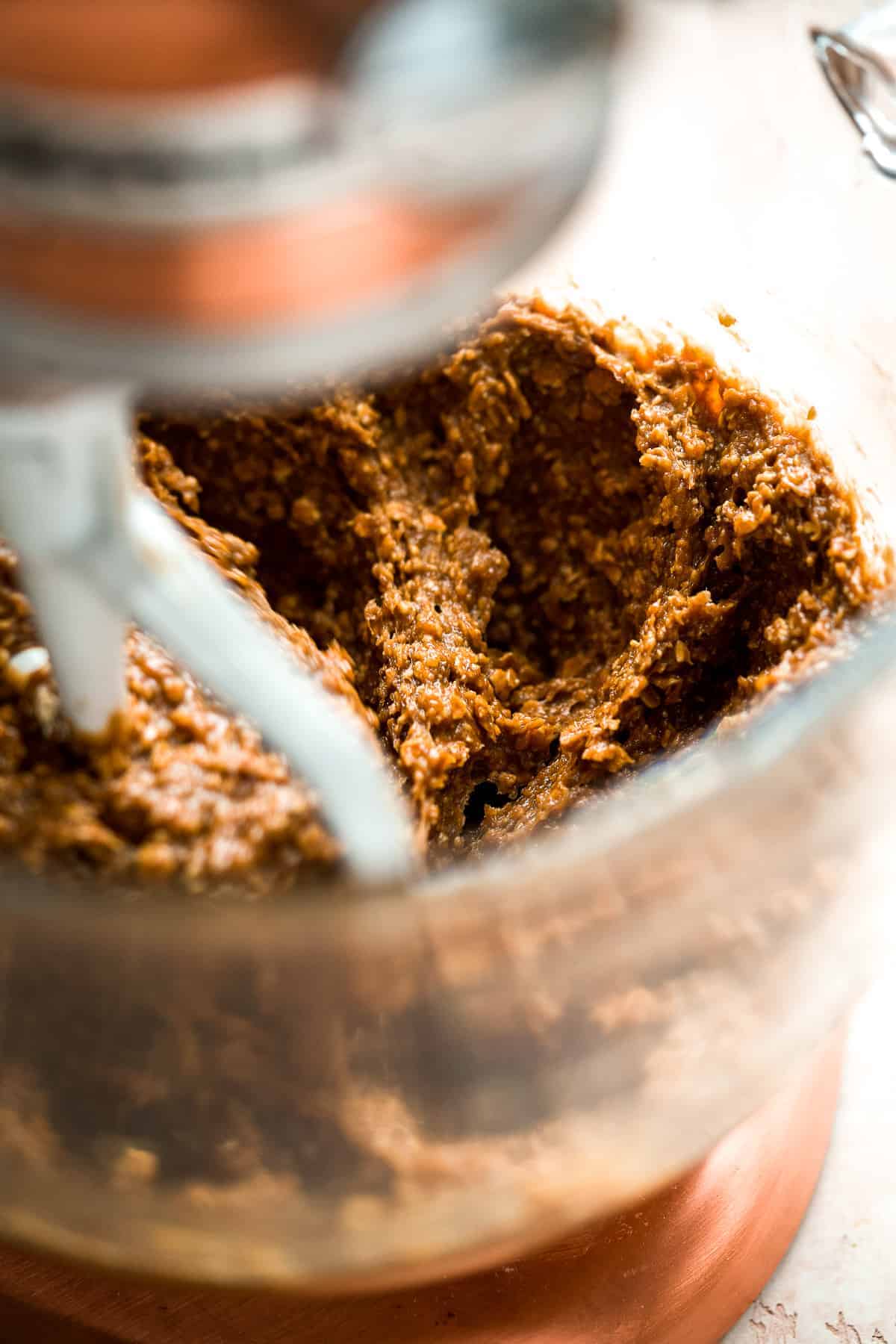 Oatmeal cookie batter in the bowl of a stand mixer with a beater.