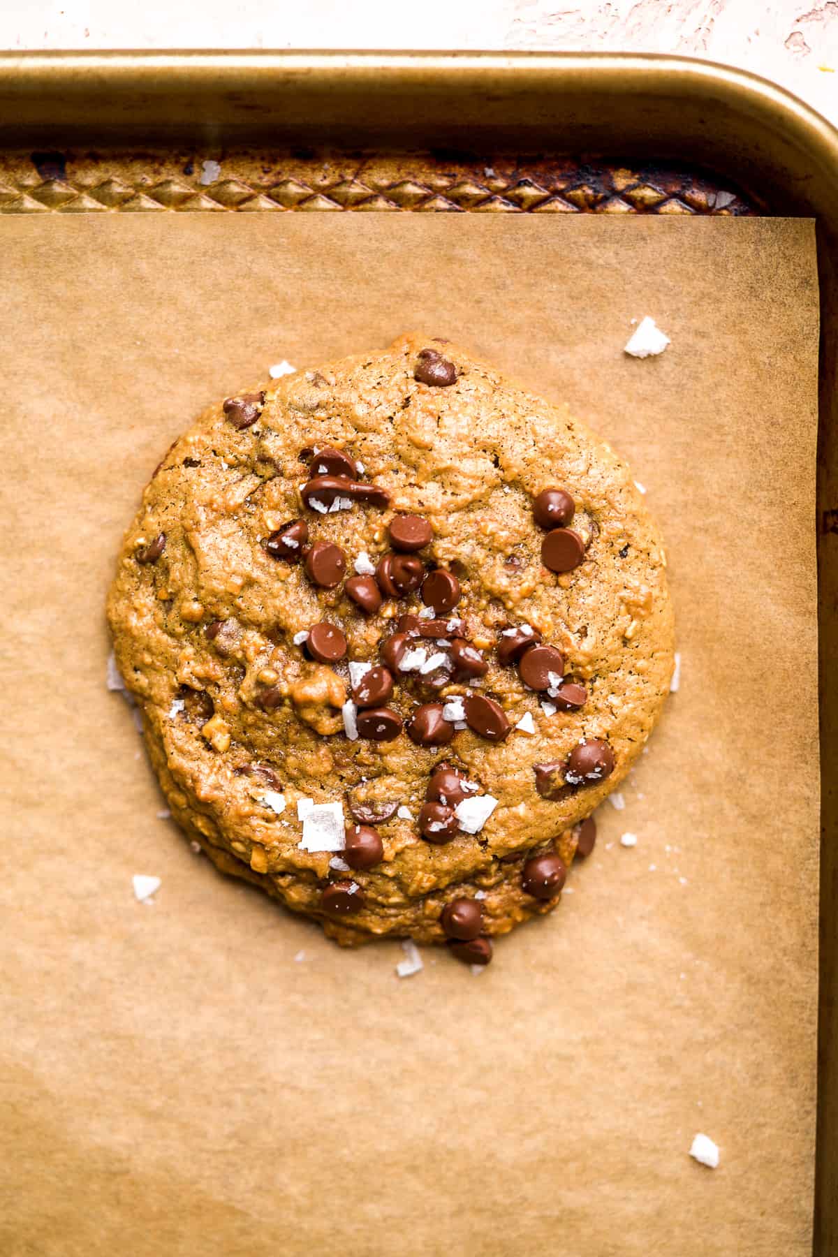 Round cookie with chocolate chips and sea salt on top in a baking pan,