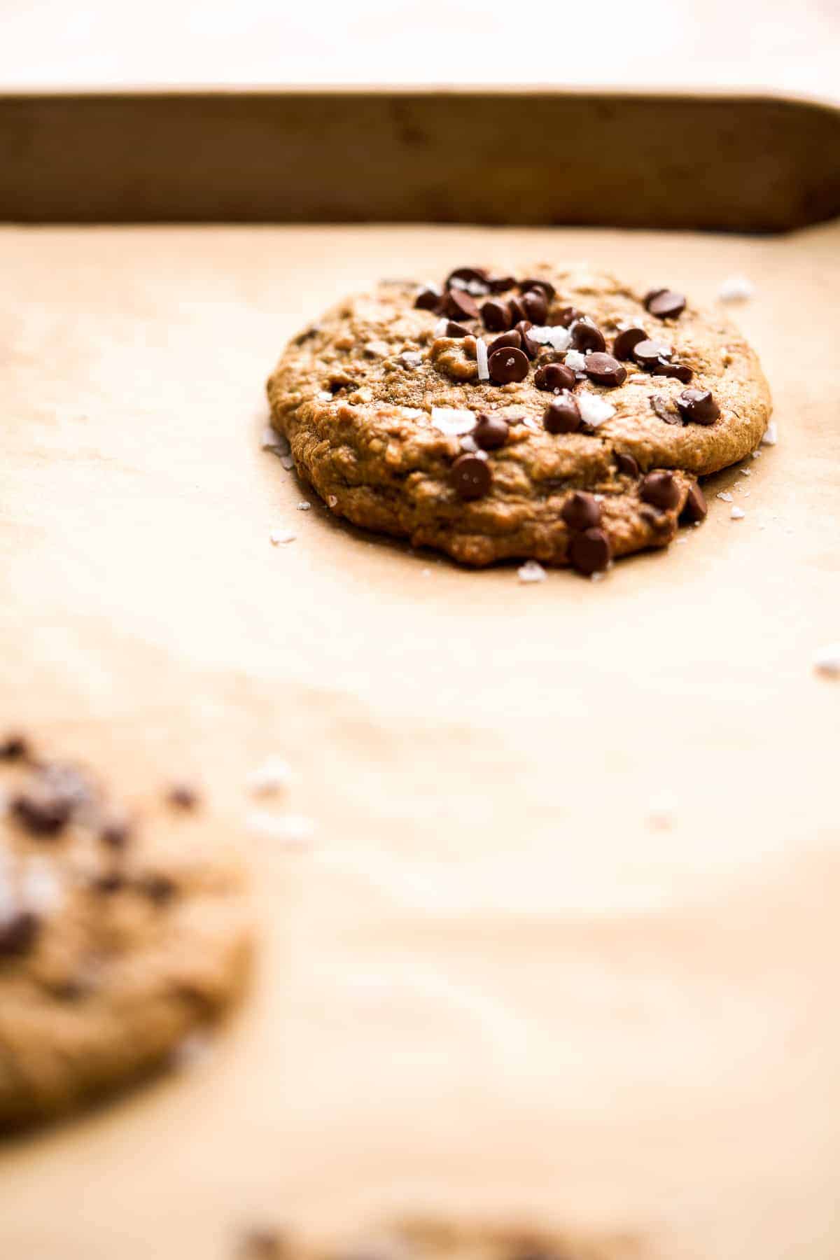 Baked cookie with chocolate chips and sea salt on top on a baking sheet.