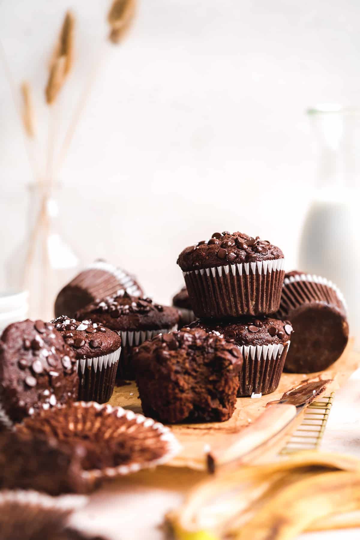 Chocolate muffins stacked on top of each other and scattered on cooling rack.