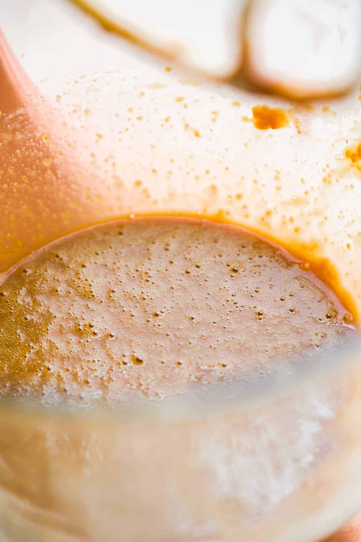 Glass mixing bowl with tan mixture.