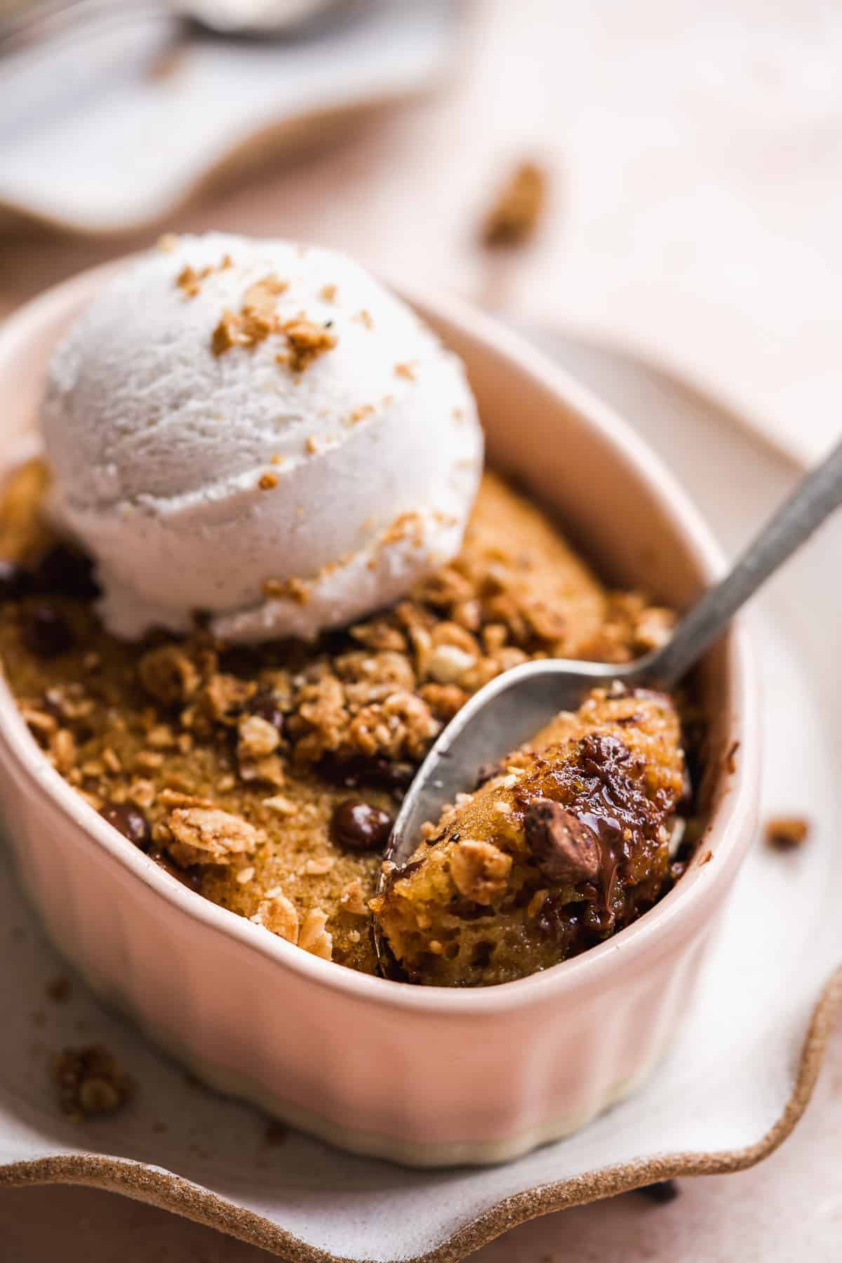 Spoon digging into a ramekin with chocolate chip cake.