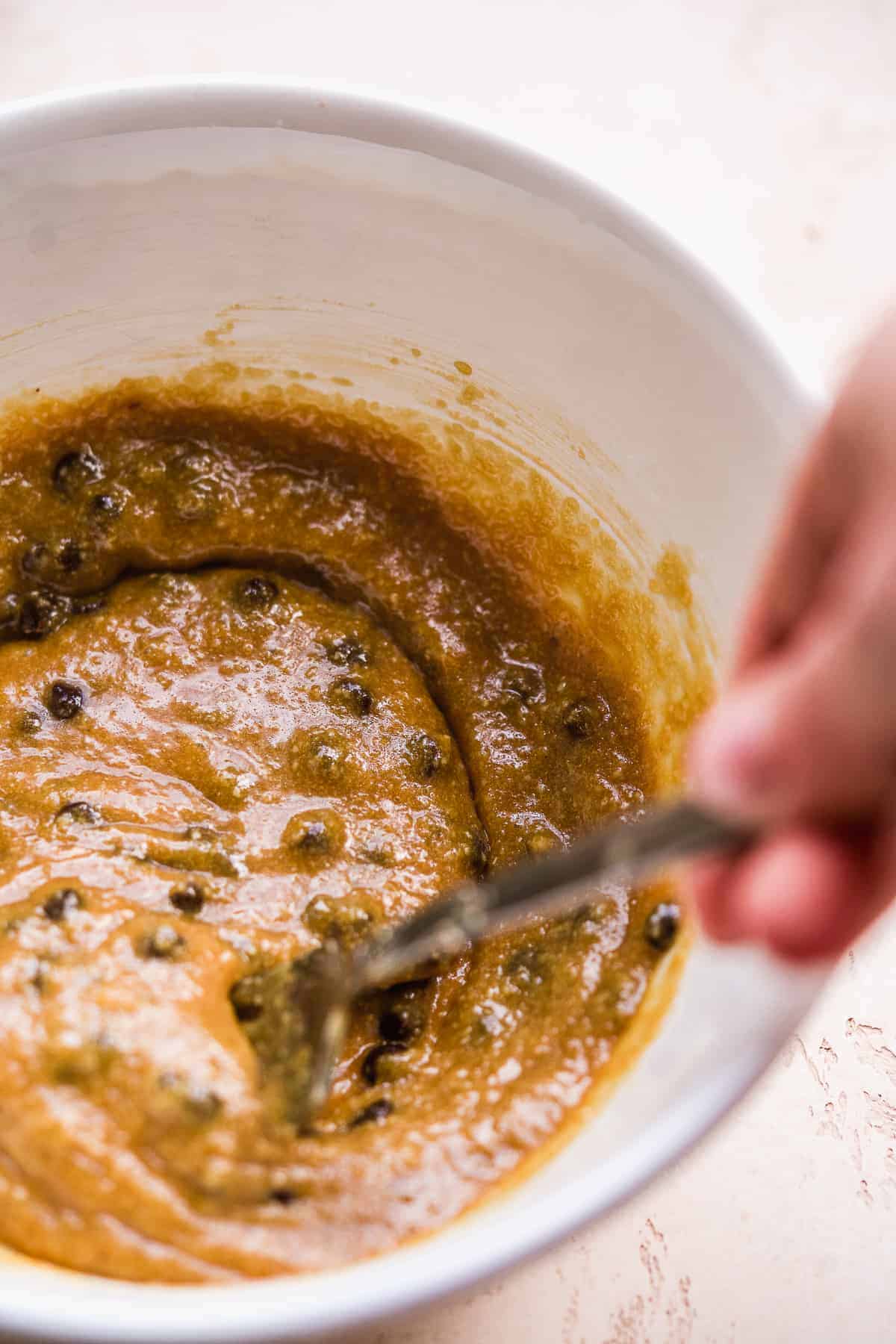 Chocolate chips being mixed into cake batter.