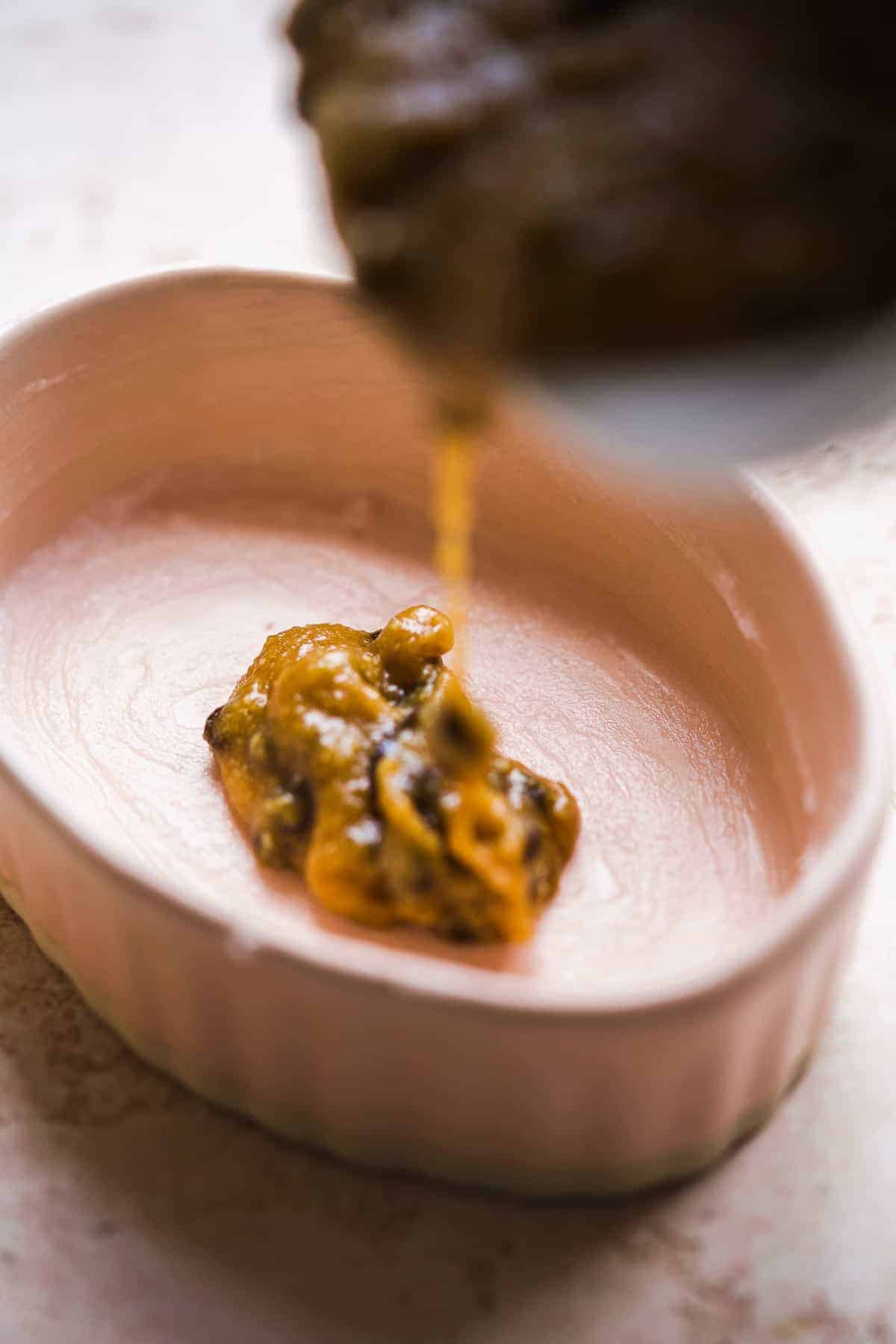 Batter being poured into an oval ramekin.