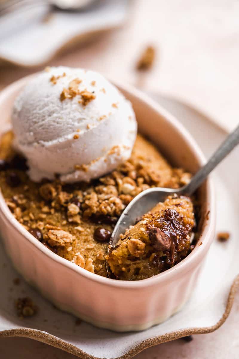 Chocolate chip mug cake in a pink bowl with a scoop of ice cream.