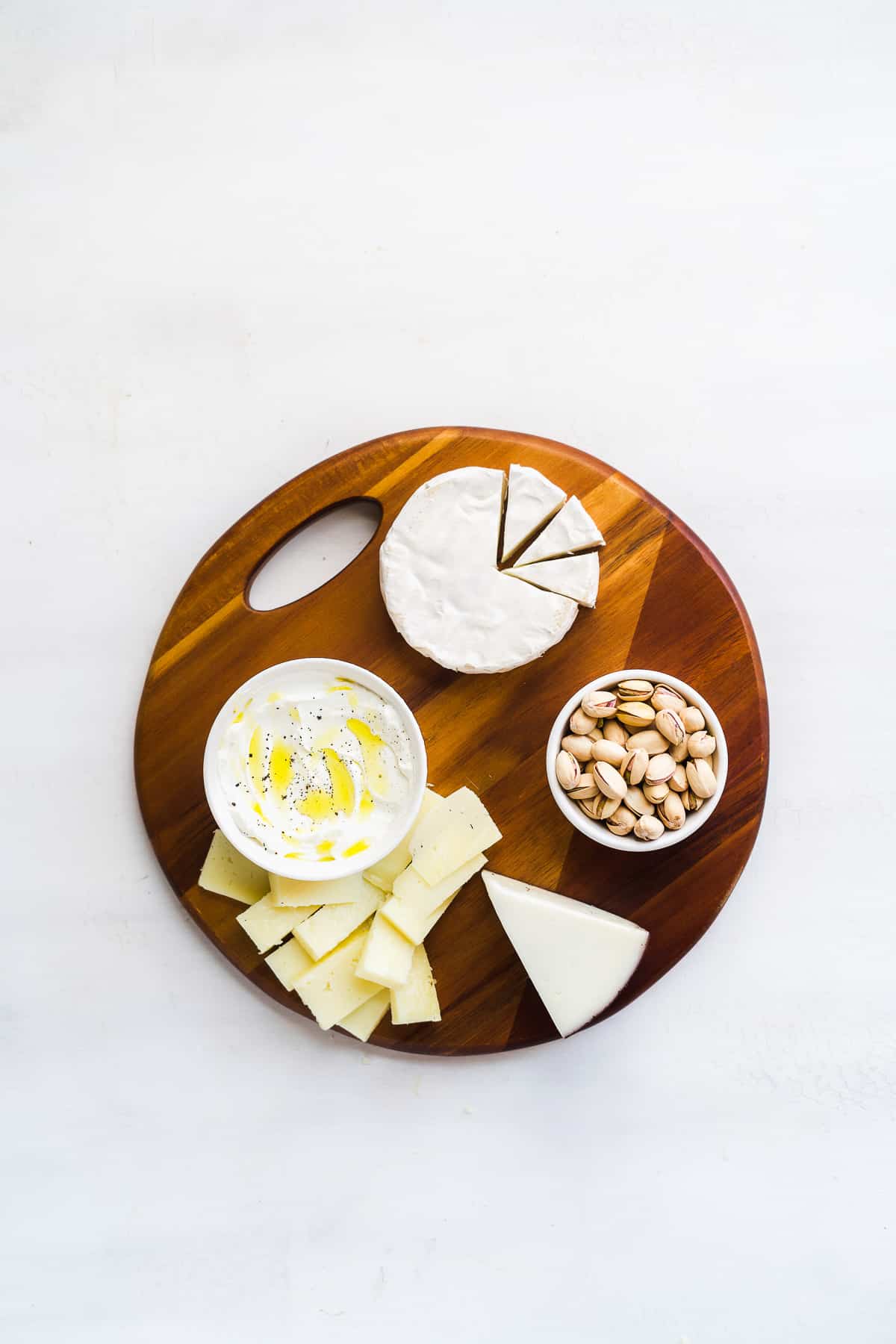 Circular platter with bowls on top and large pieces of cheese.