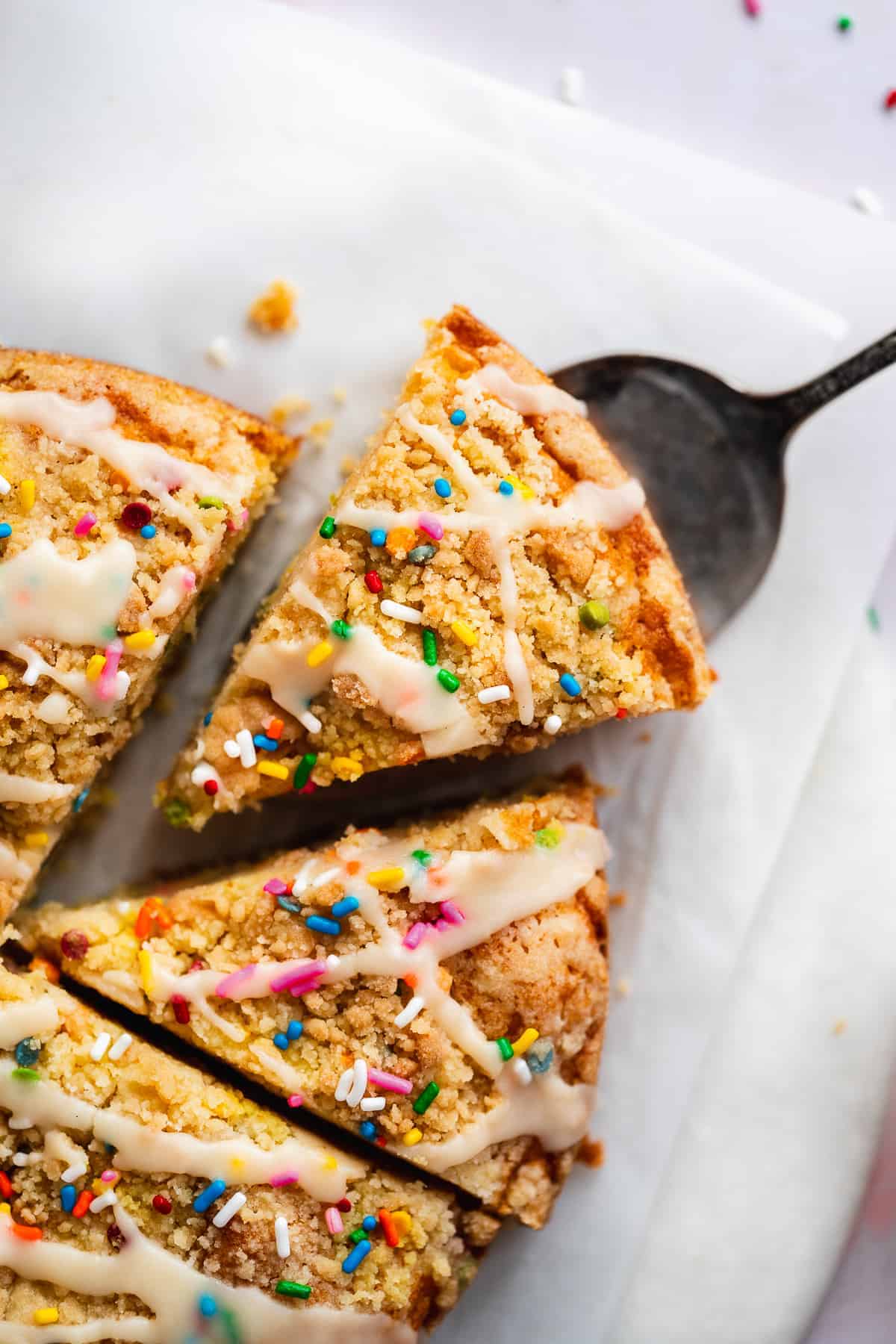 Triangular piece of coffee cake with sprinkles and a glaze on top.