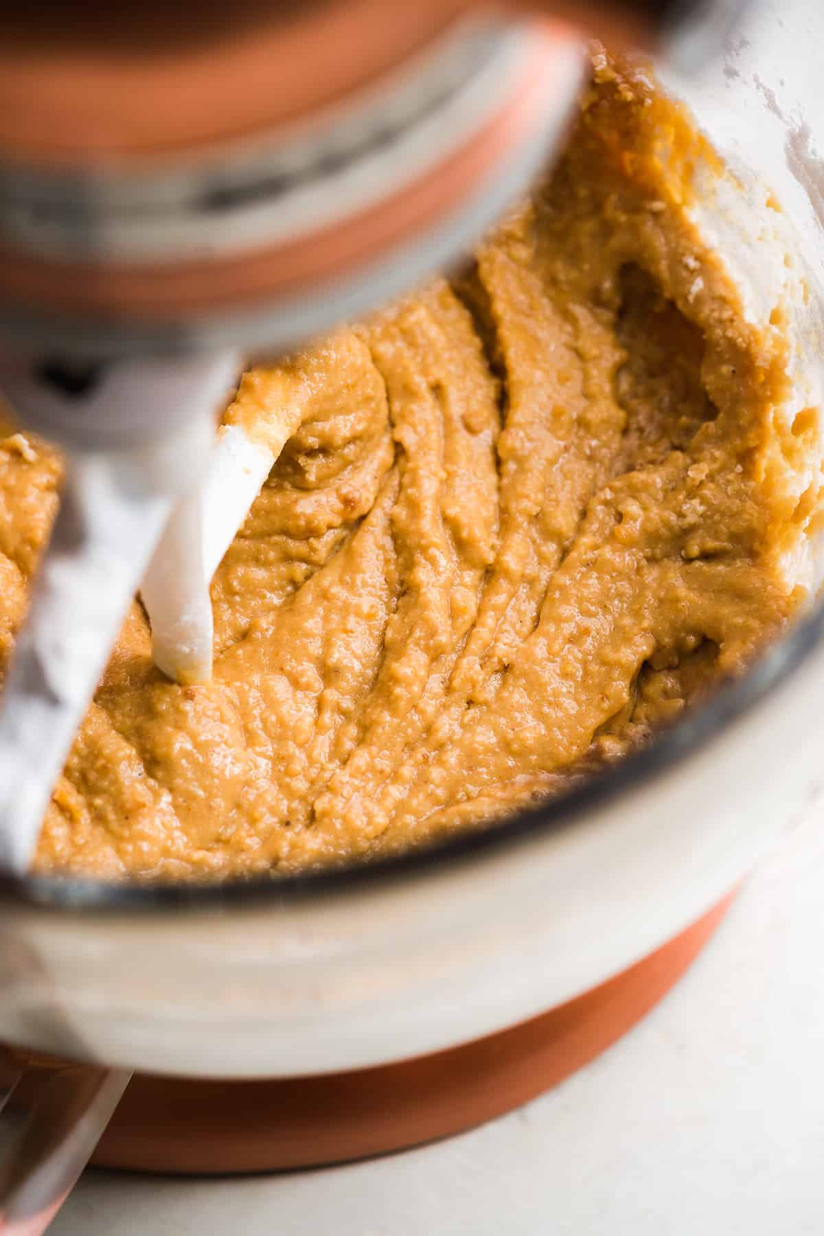 Cake batter being mixed inside a glass bowl with a beater.