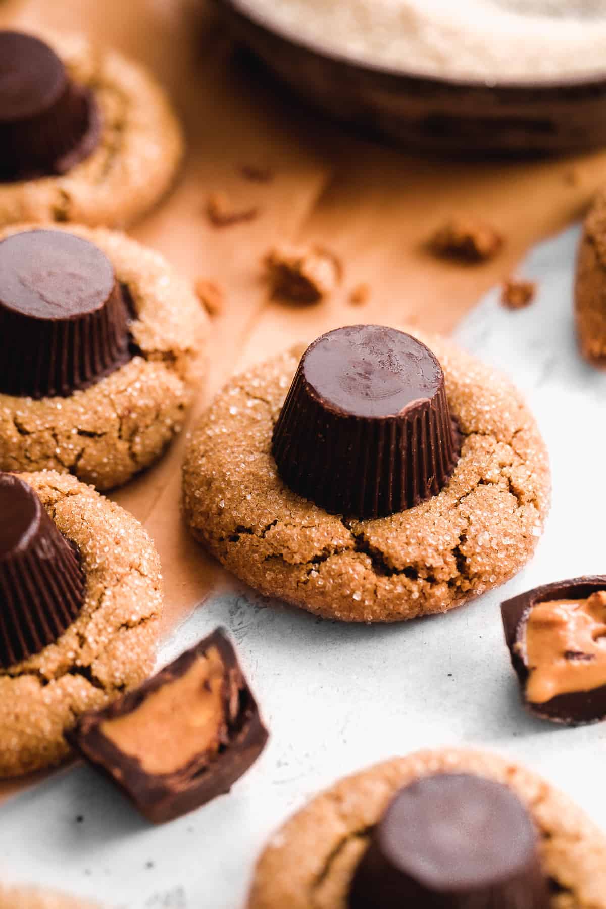 Cookies with a peanut butter cup on top and sugar coating scattered on a surface.