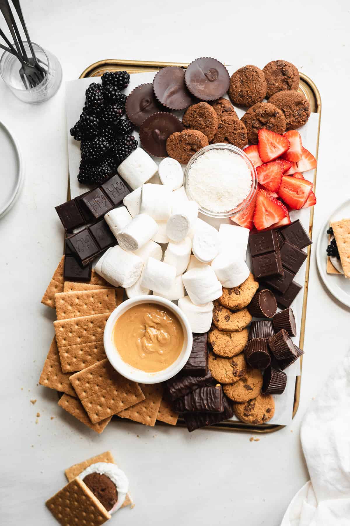 Rectangular board with sweets scattered on top on a white surface.