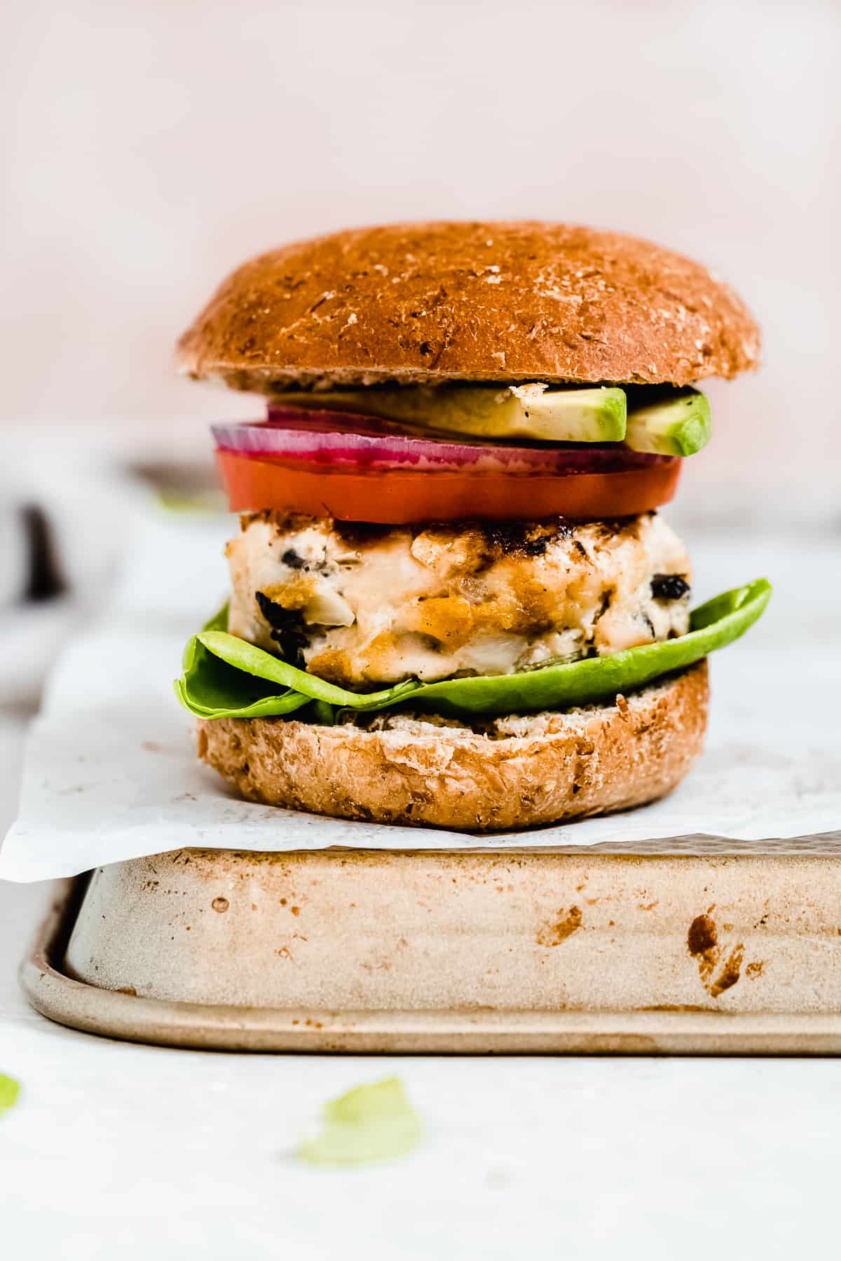 Turkey burger with lettuce and tomato and bun on top.