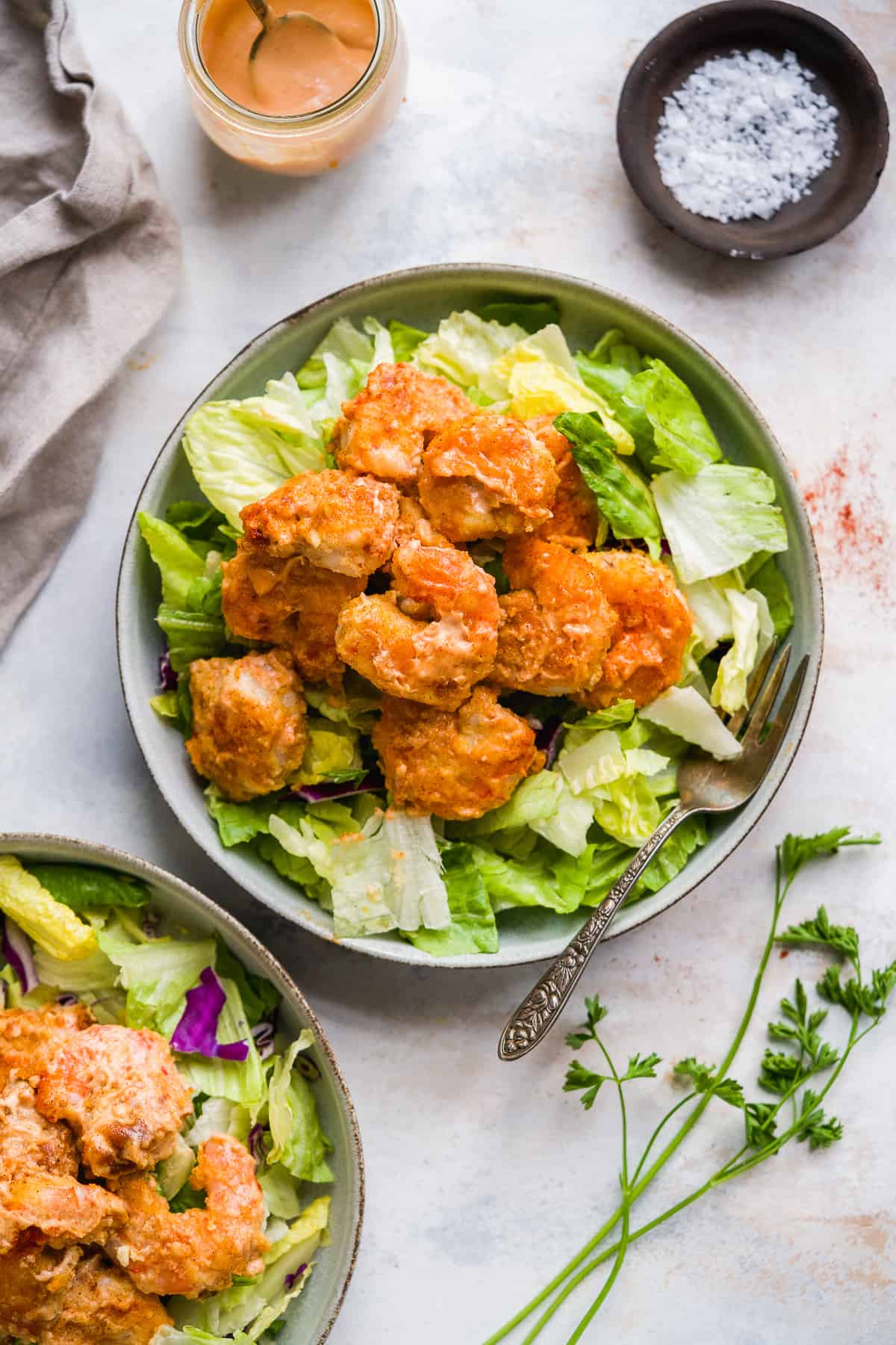 Overhead view of a plate of lettuce with bang bang shrimp on top.