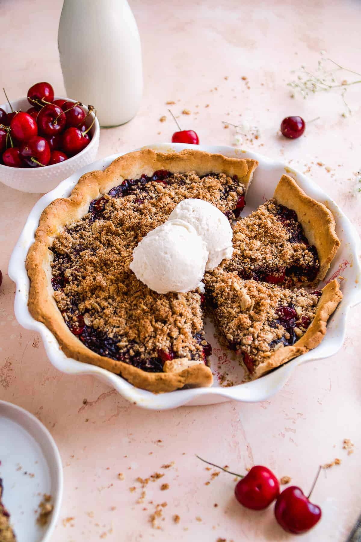 Cherry pie with a gluten free crumble on a pink surface.