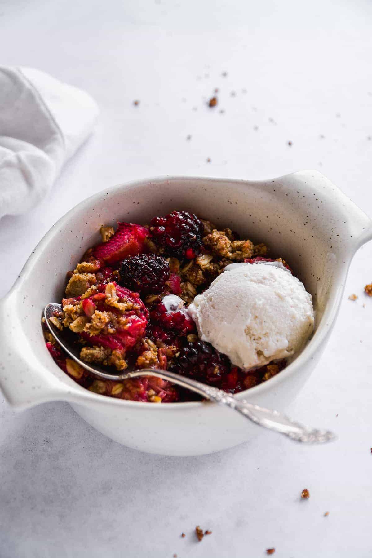 White bowl with gluten free rhubarb crisp and ice cream.