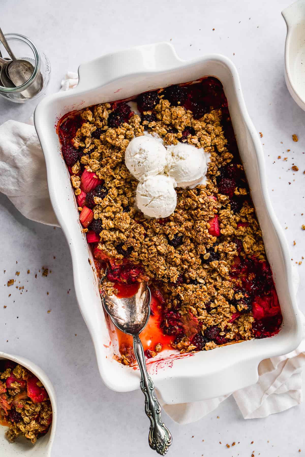 White dish with gluten free rhubarb crisp and ice cream scoops on top.