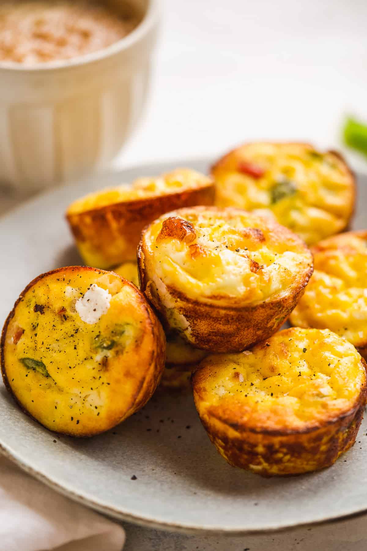 Ricotta egg muffins on a plate with a mug of coffee in the background.